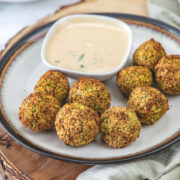 a plate of air fryer falafel served with tahini sauce on a wooden board.