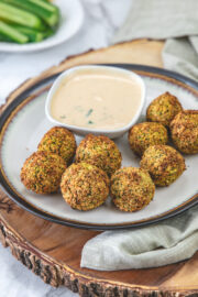 a plate of air fryer falafel served with tahini sauce on a wooden board.