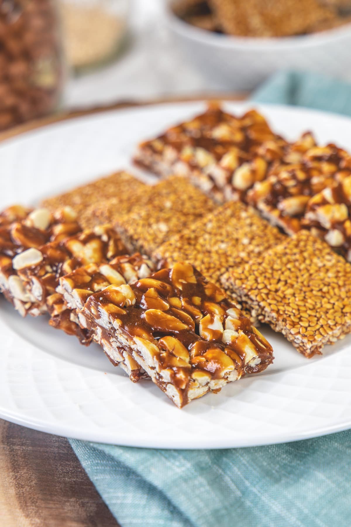 peanut chikki and til chikki served in a white plate and napkin underneath.