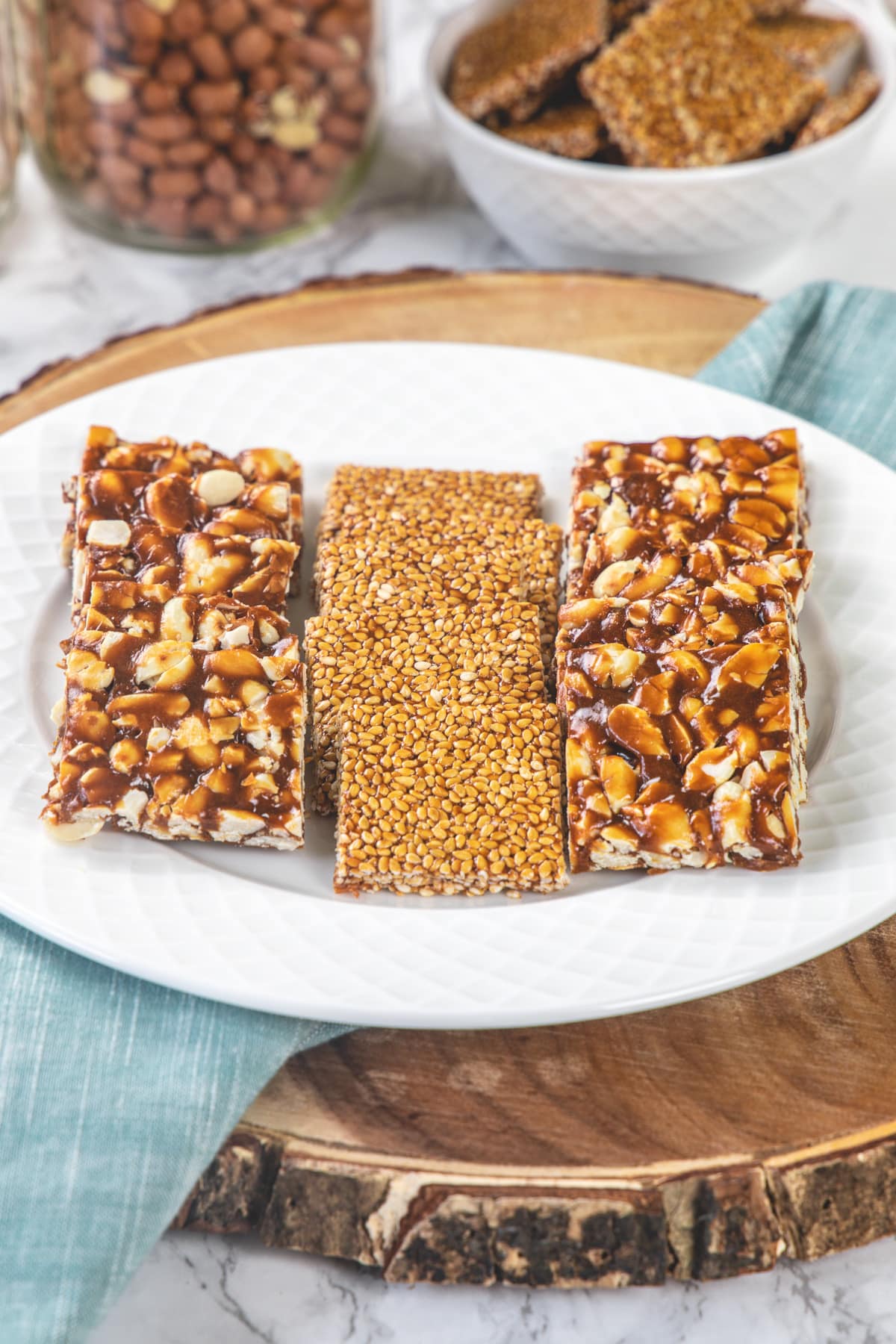 3 lines of chikki in a plate and few more in a bowl in the background.