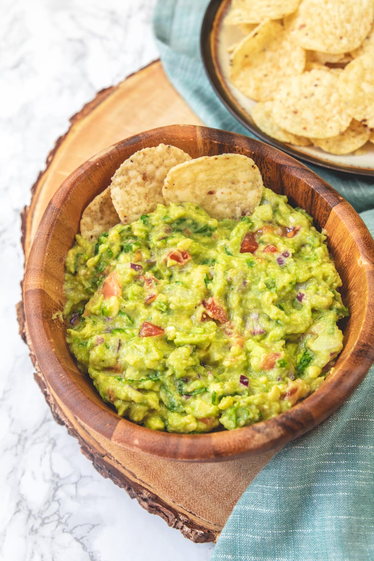 Spicy guacamole served in a wooden bowl with chips.