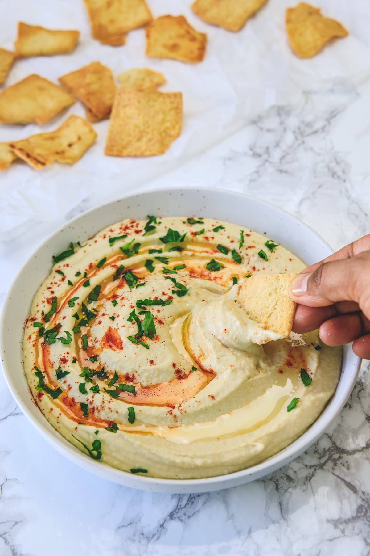 Scooping hummus with pita chips.