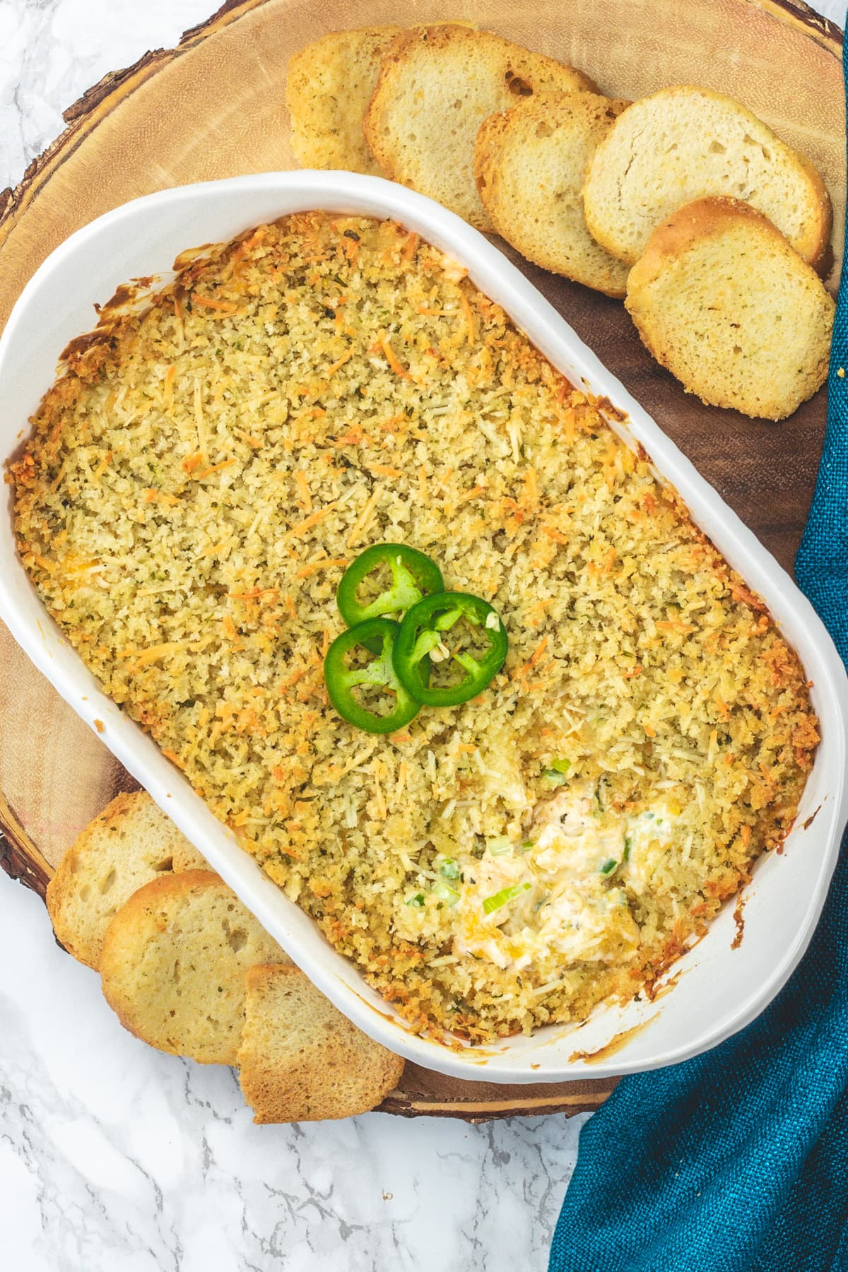 Top view of jalapeno popper dip served with crostini on a wooden board.