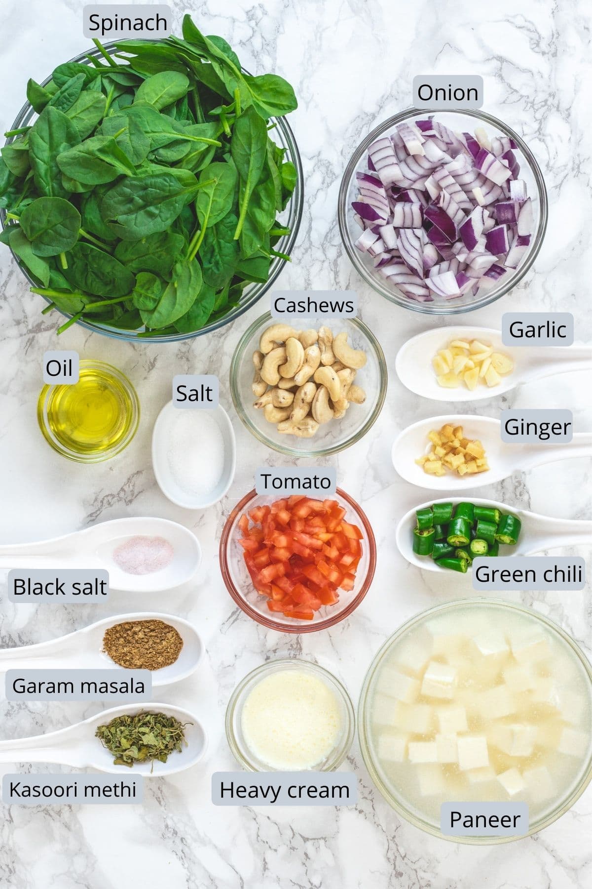 Palak paneer ingredients in individual bowls and spoons.