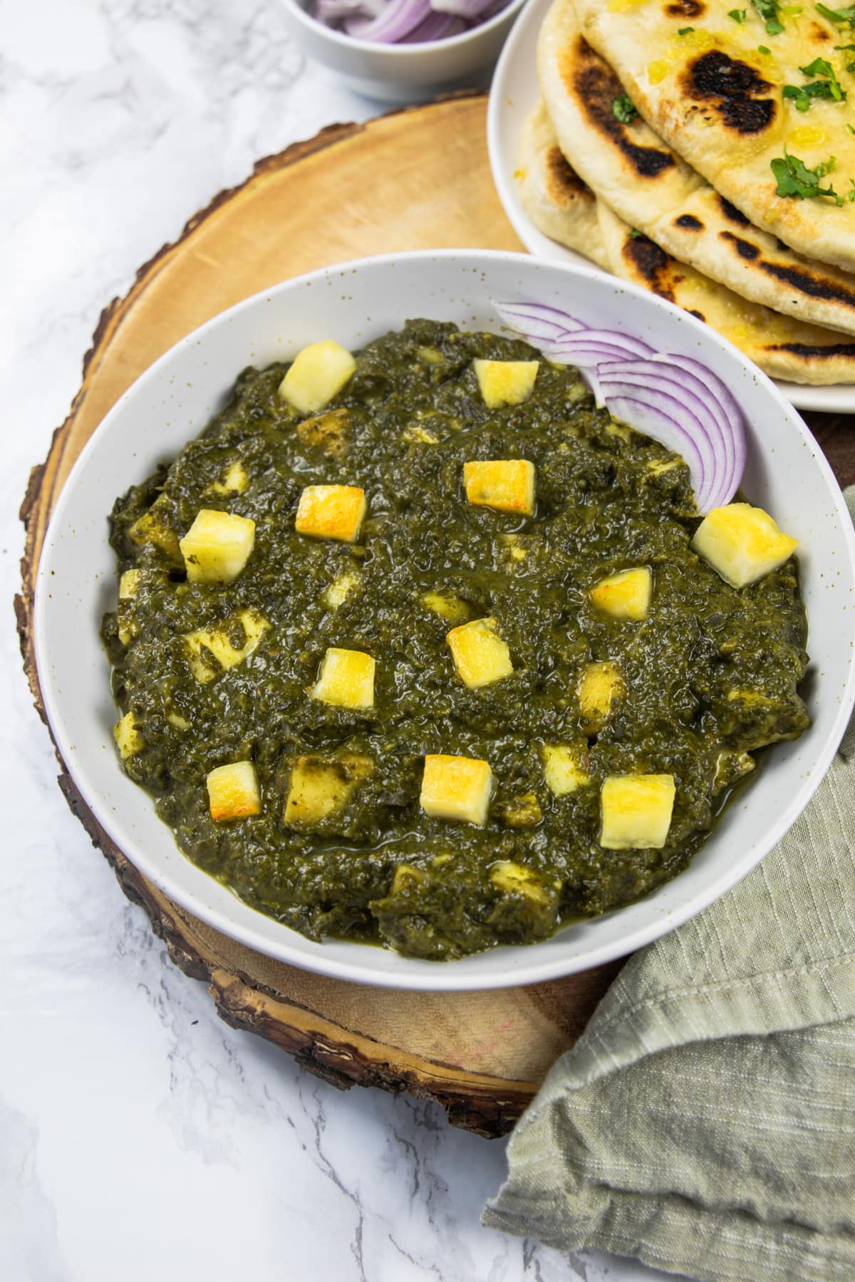 saag paneer served with sliced onions and naan.