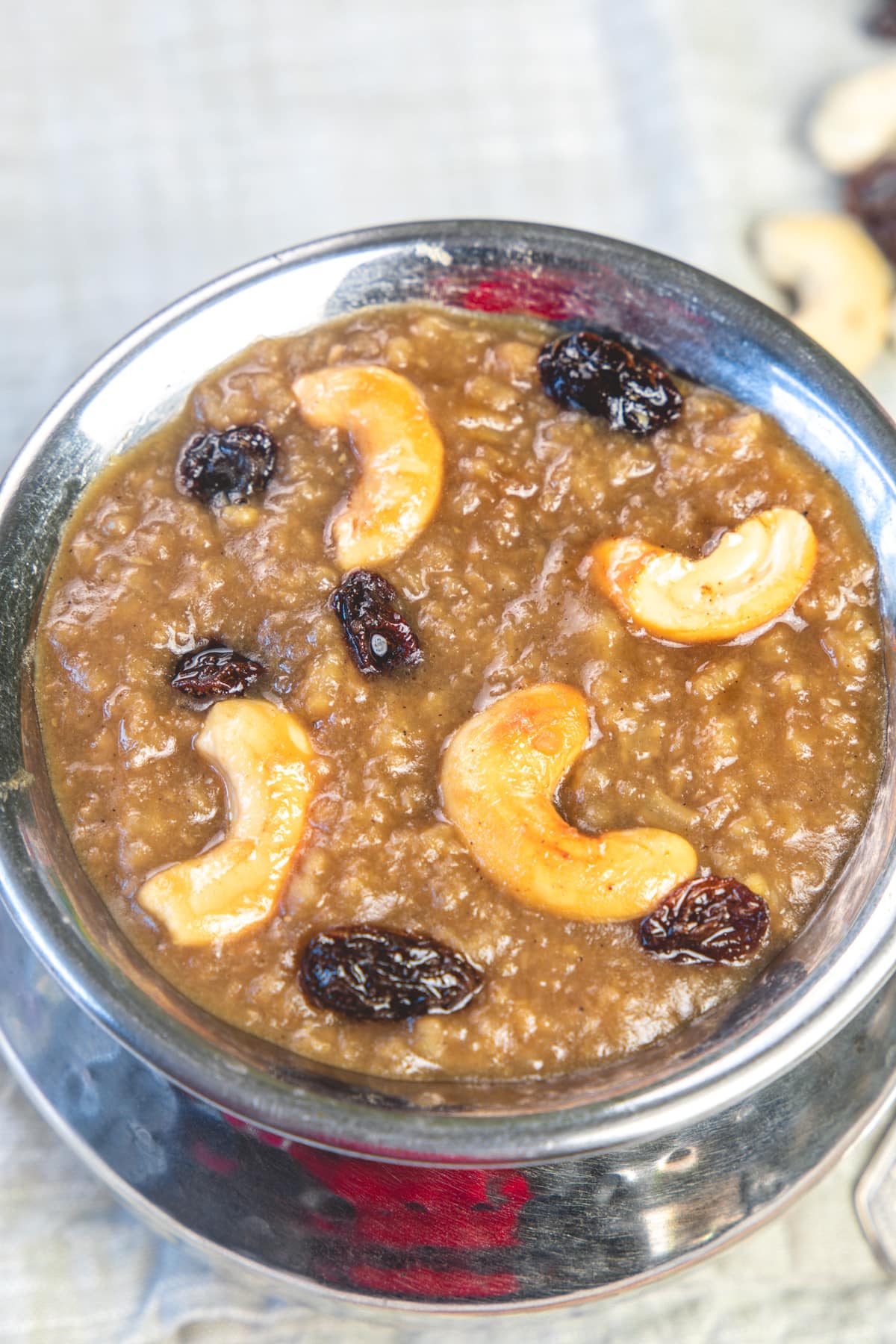 Sweet pongal in a steep serving dish garnished with cashews and raisins.