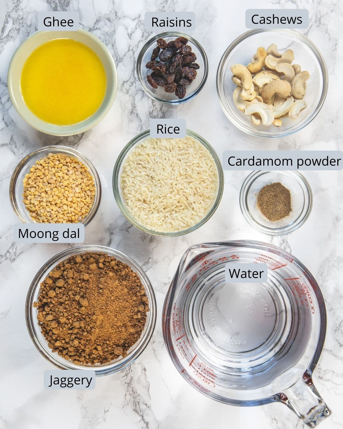 Ingredients used in sweet pongal in individual bowls on marble back ground.
