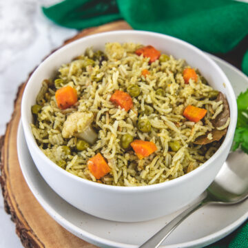 Coriander rice in a white bowl with a spoon on side on the wooden board.