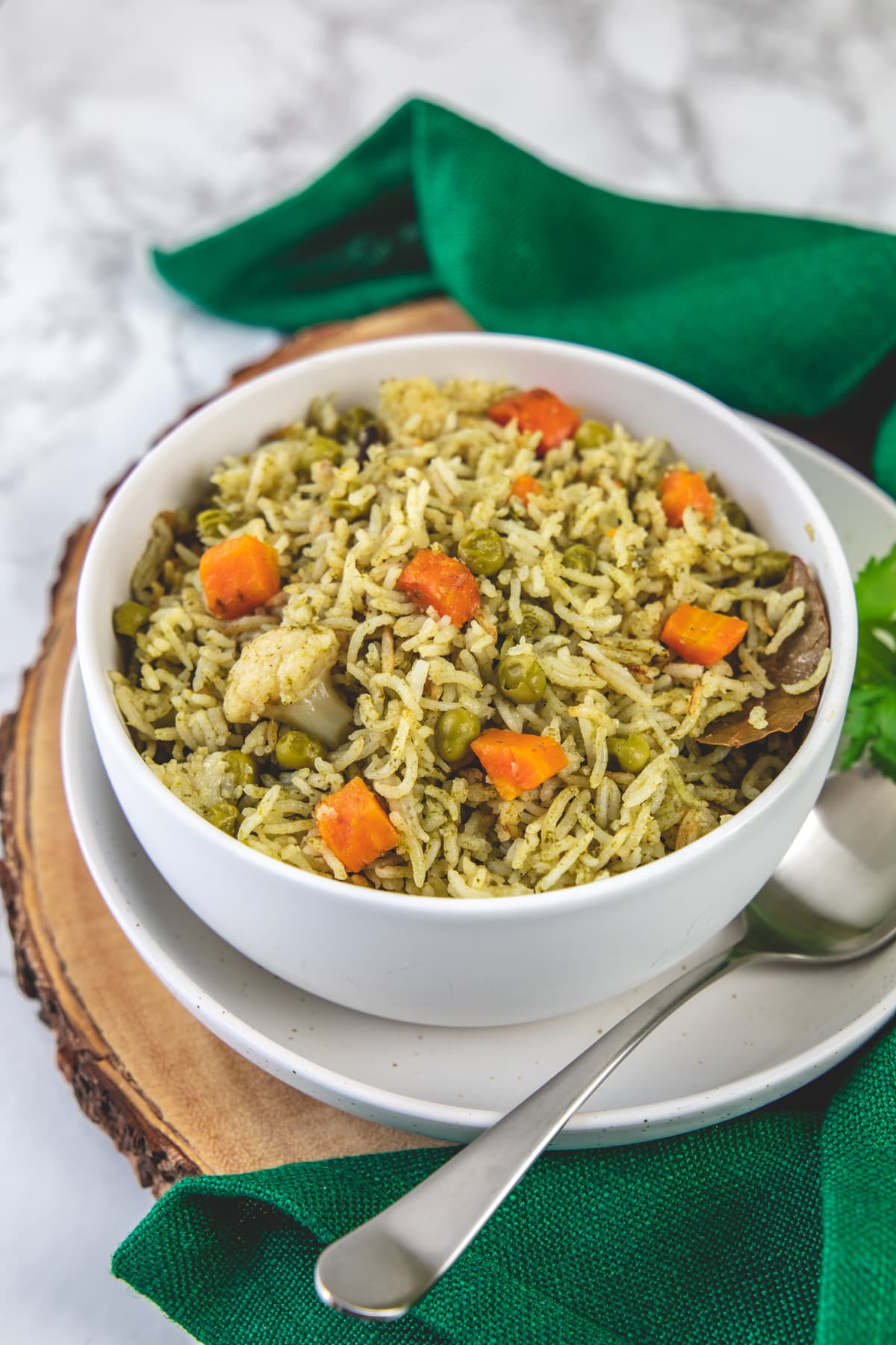 Coriander rice in a white bowl with a spoon on side on the wooden board.