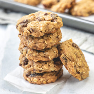 A stack of eggless oatmeal cookies on a piece of parchment paper.