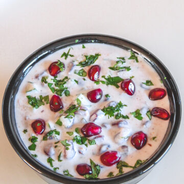 Pomegranate raita garnished with cilantro and arils.