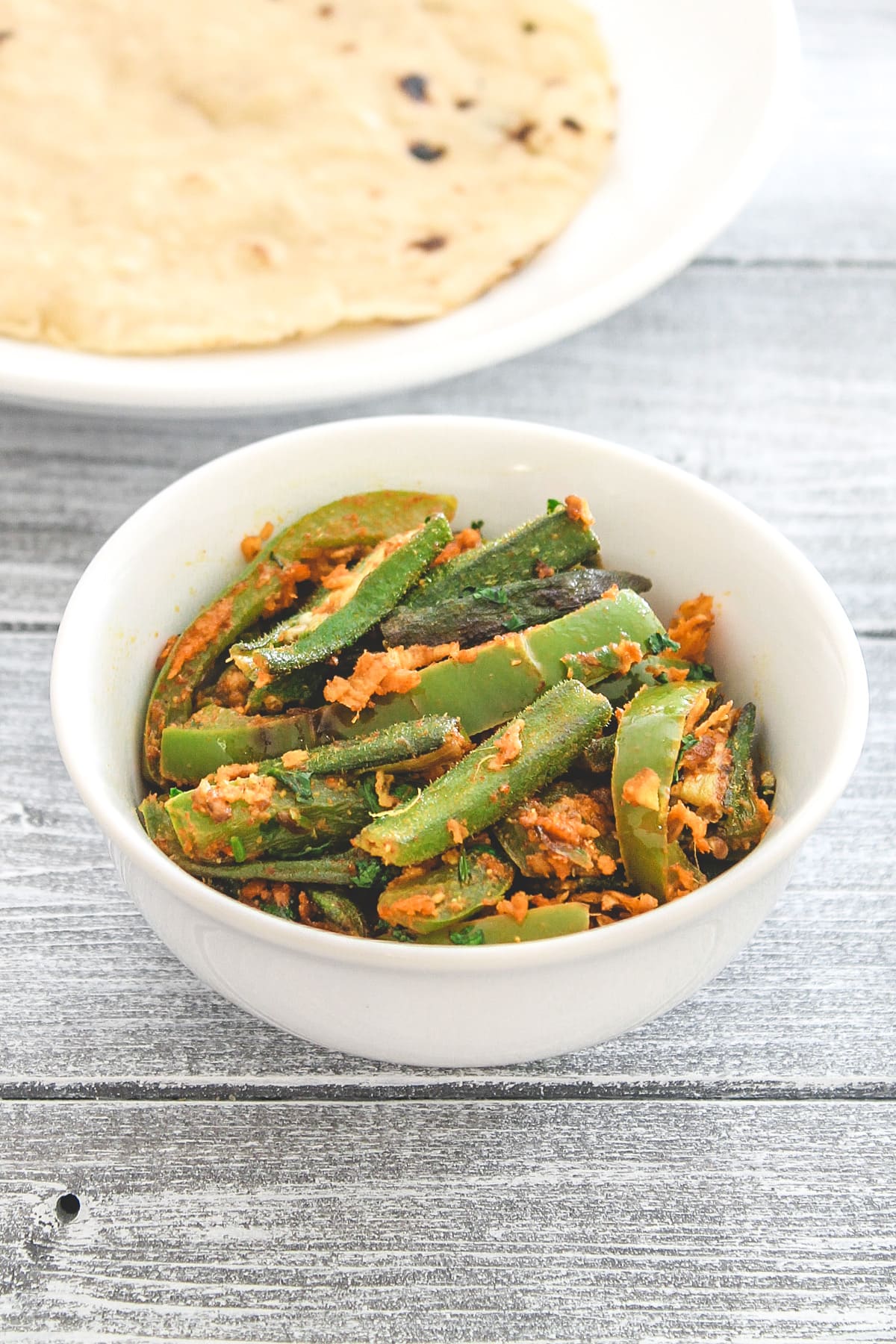 Bhindi capsicum served in a white bowl with roti.