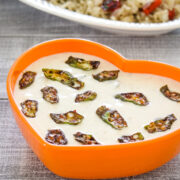 Bhindi raita in a orange bowl with pulao served on the side.