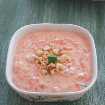 Carrot raita garnished with crushed peanuts and cilantro.