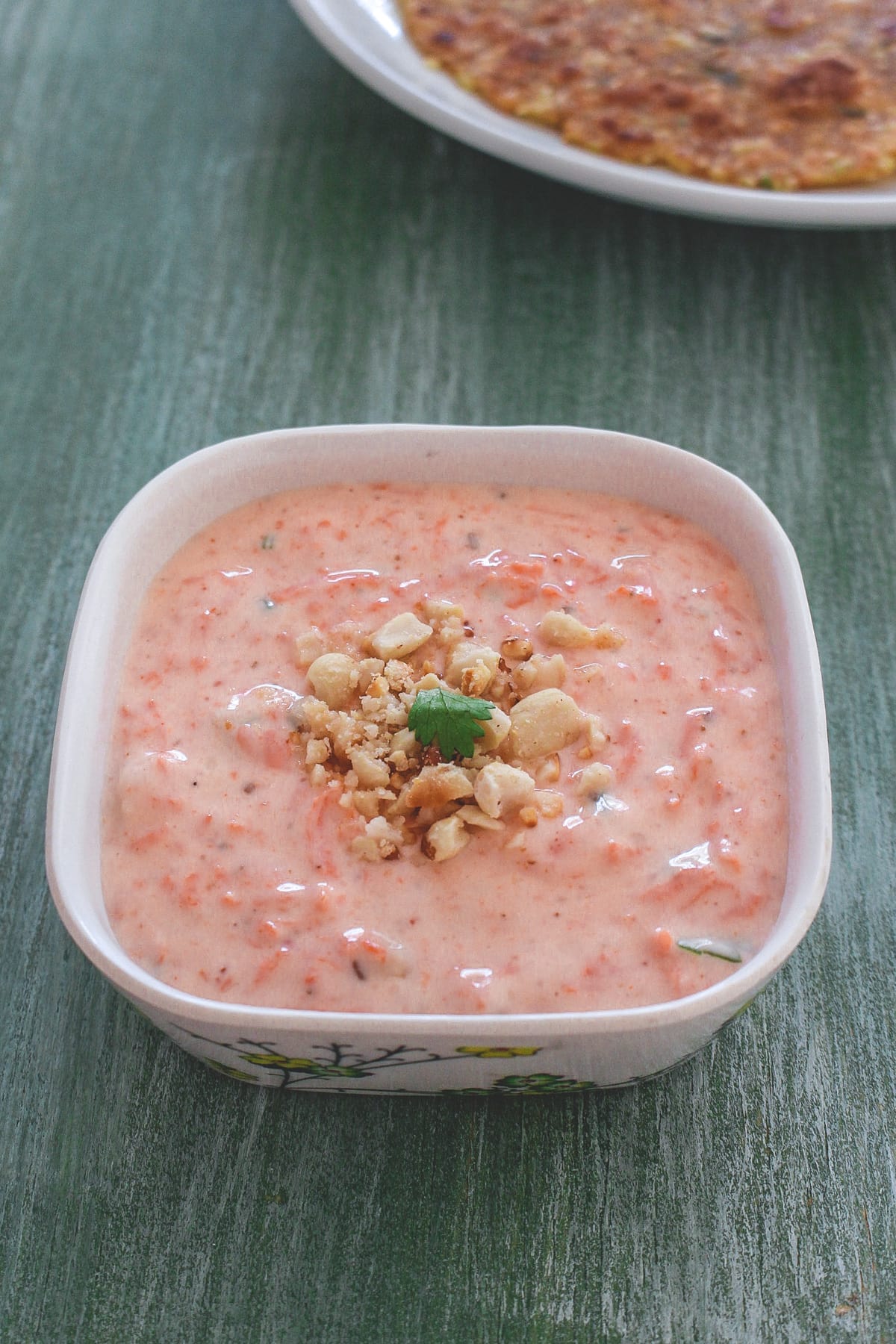 Carrot raita garnished with crushed peanuts and cilantro.