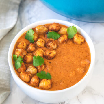 chickpea tikka masala in a bowl garnished with cilantro and napkin on the side.