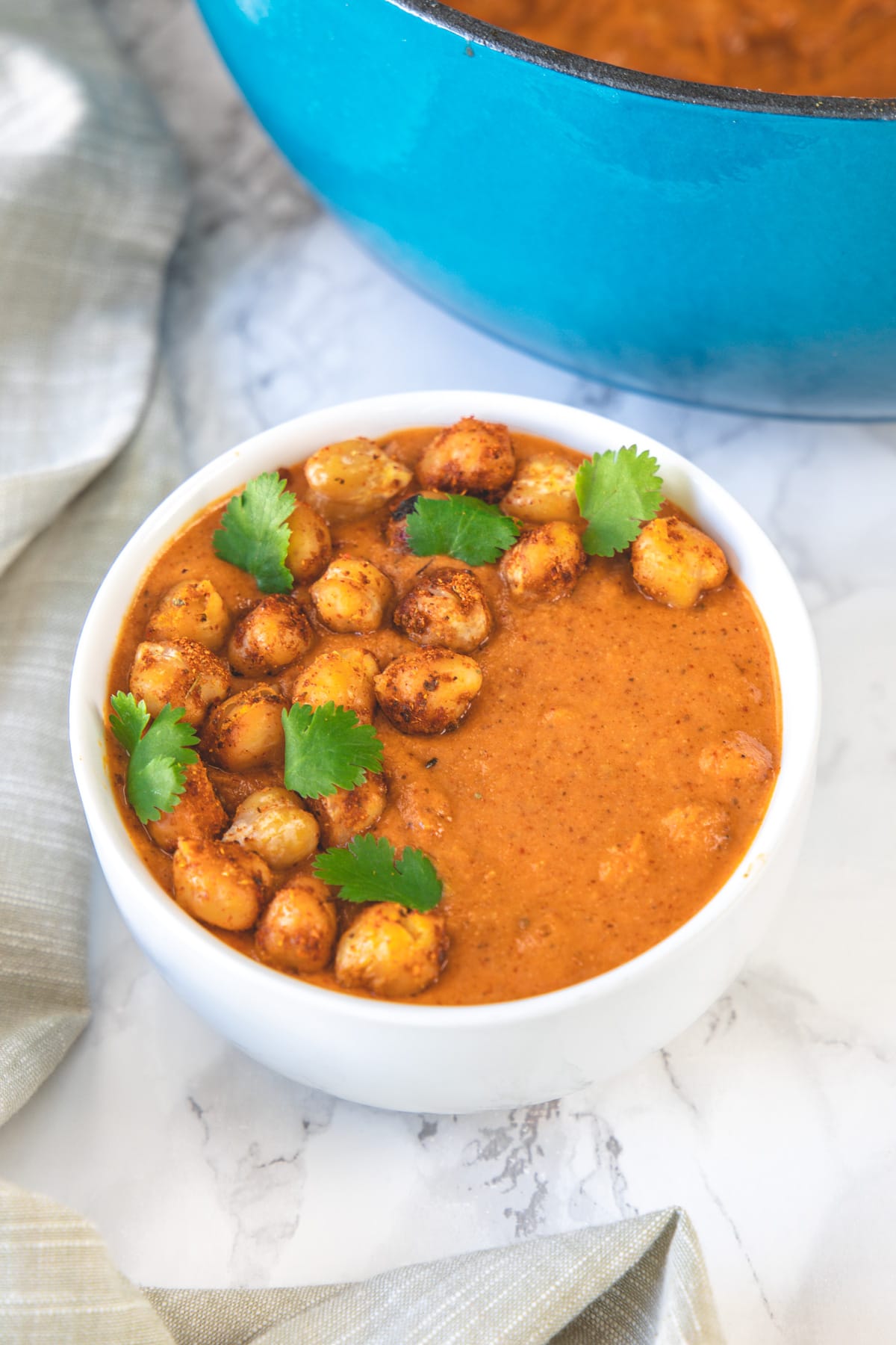 chickpea tikka masala in a bowl garnished with cilantro and napkin on the side.