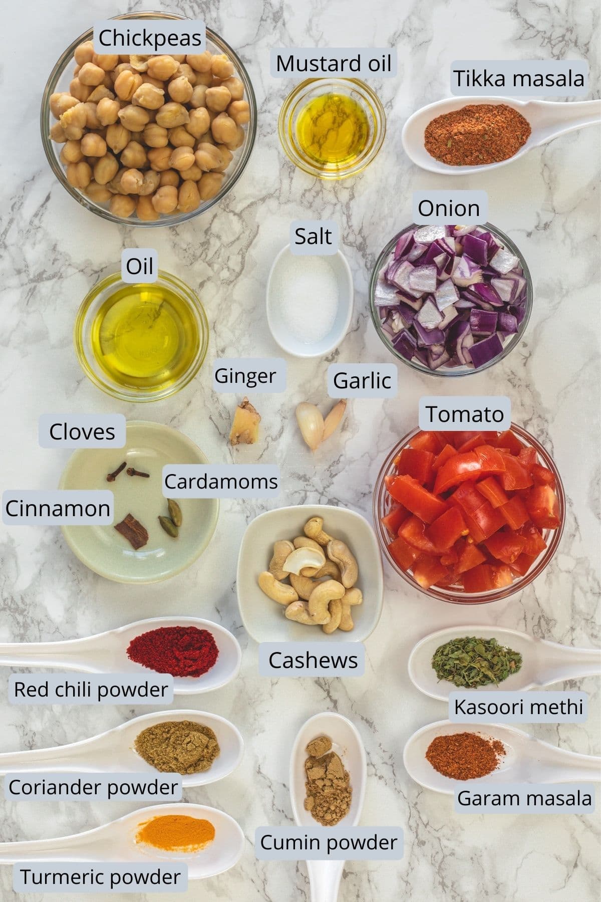 Ingredients used in chickpea tikka masala recipe with labels on a marble surface.