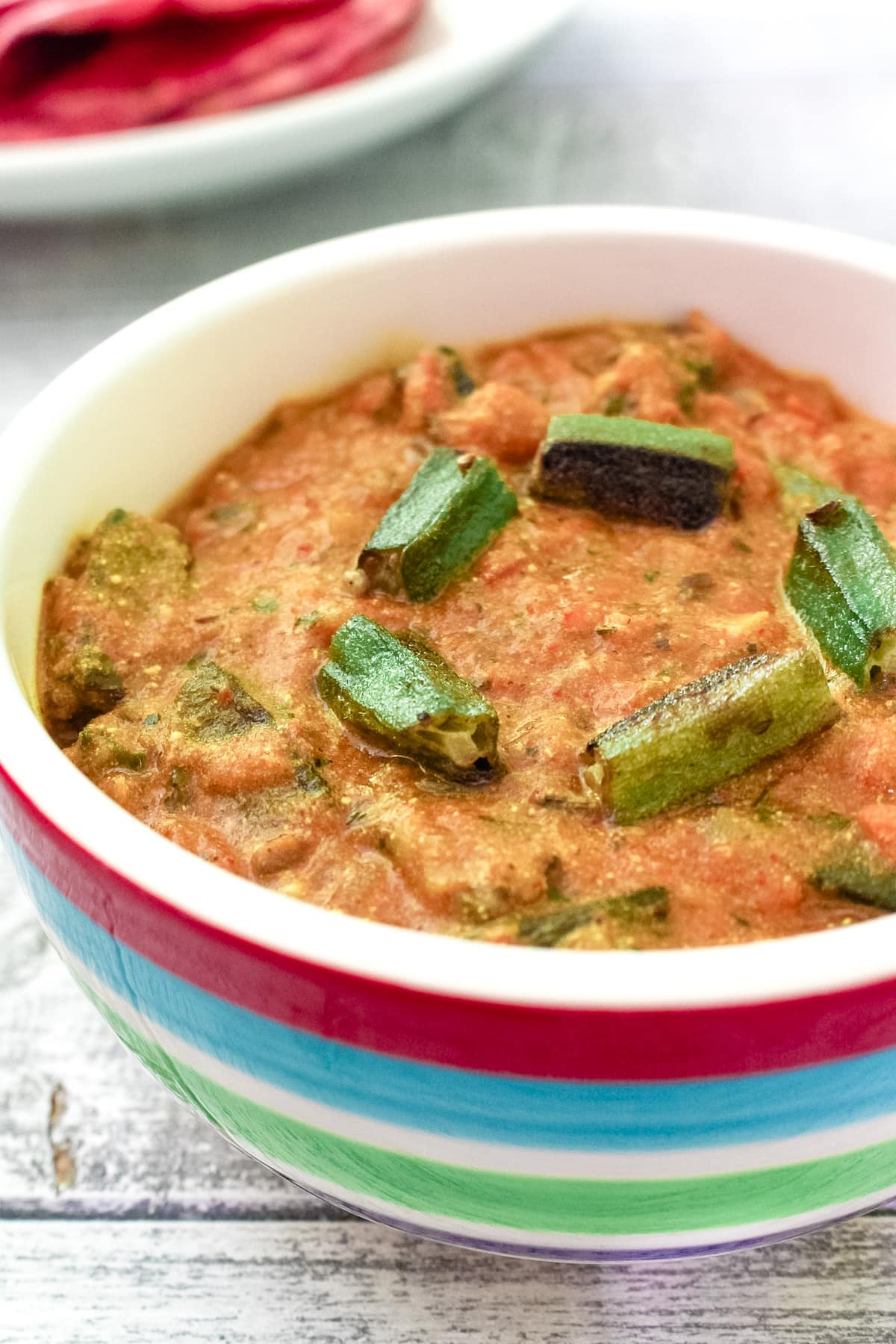 Dahi bhindi served in a bowl and garnished with few cooked okra pieces.