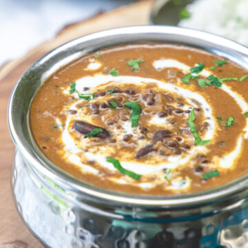 Dal makhani served in handi on a wooden board.