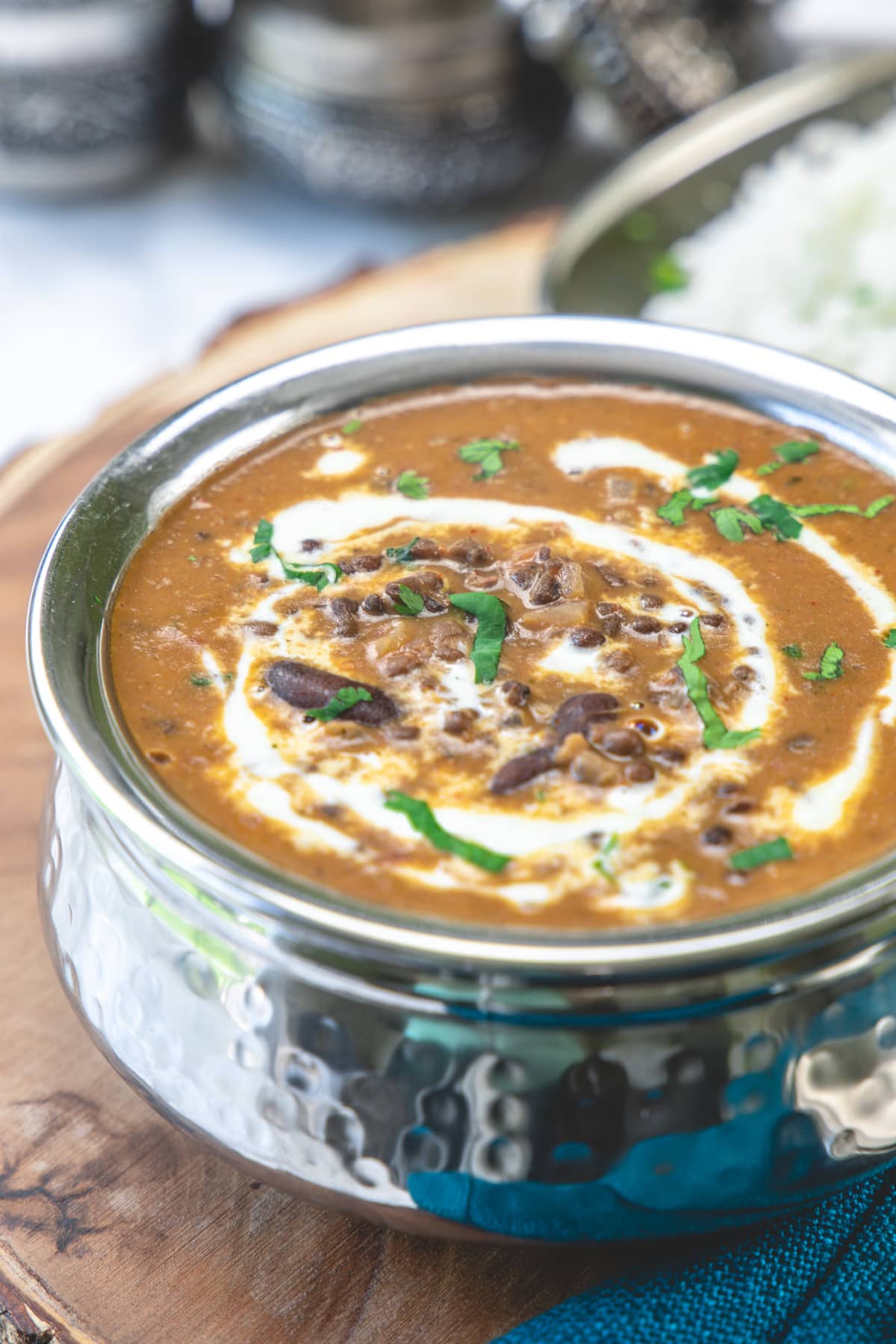 Dal makhani served in handi on a wooden board.