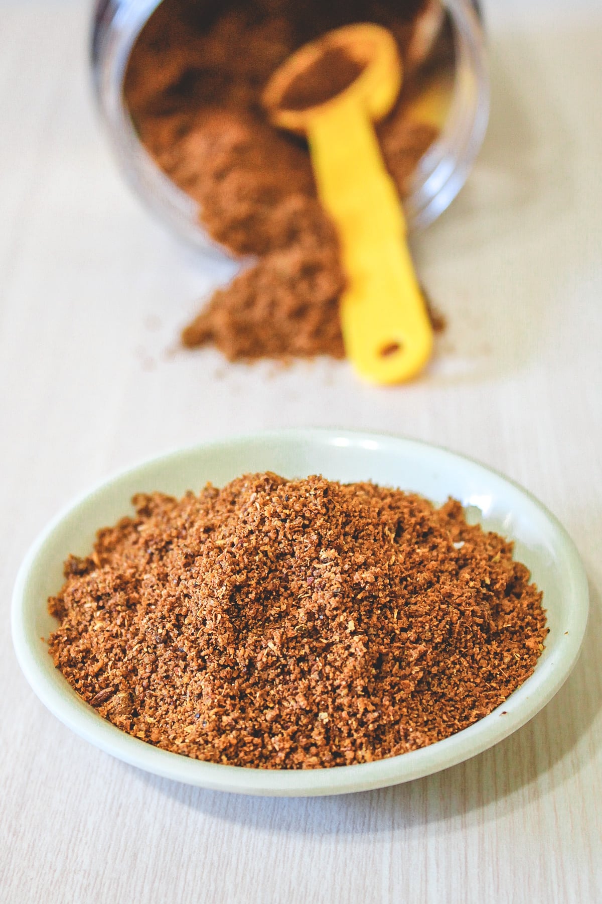 Goda masala in a shallow bowl and more in a container in back.