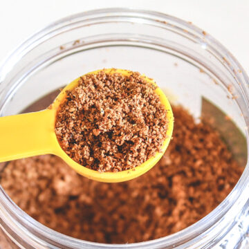 A spoonful of goda masala taking fron the container.