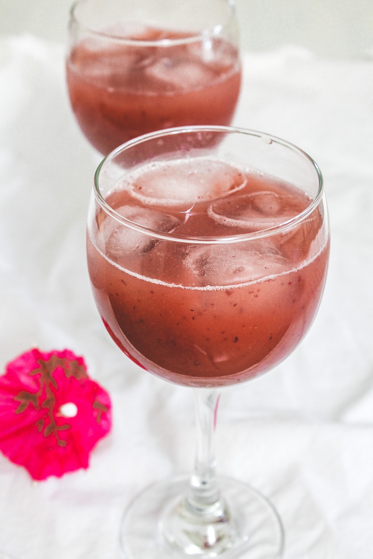 2 glasses of grape juice with ice cubes in it.