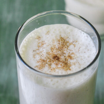 Sweet lassi garnished with cardamom powder.