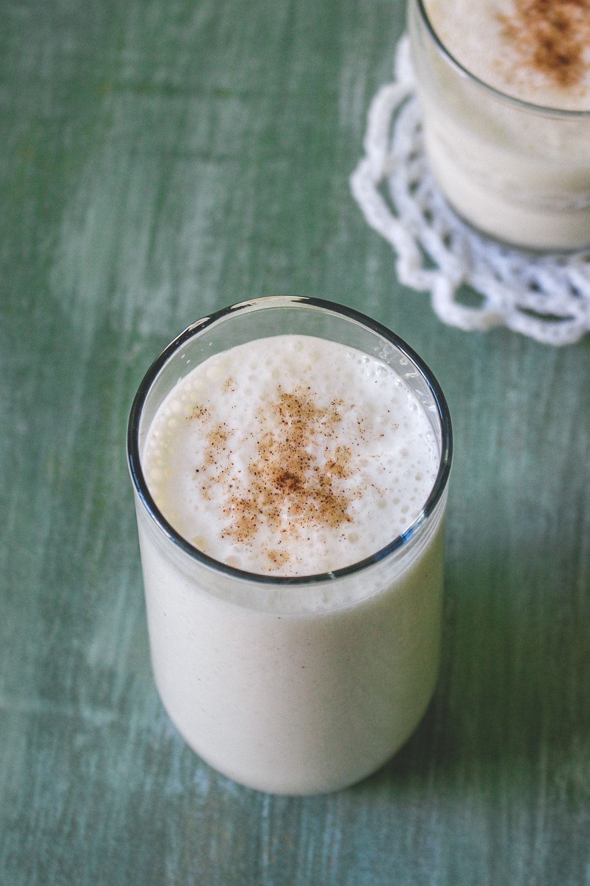 2 glasses of sweet lassi garnished with cardamom powder.