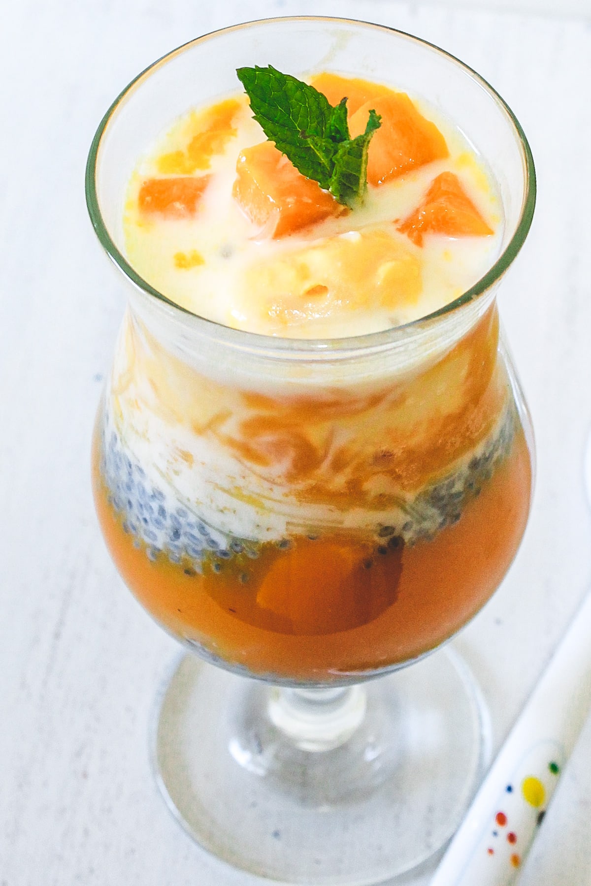 mango falooda in a glass garnished with mint leaves.