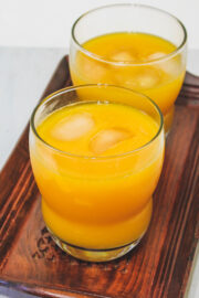 2 glass of mango juice in a wooden tray.