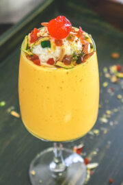 Mango mastani garnished with ice cream, nuts, turri frutti and cherry.