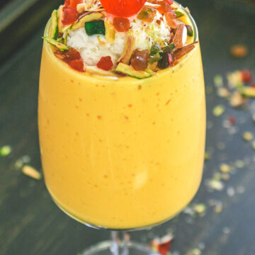 Mango mastani garnished with ice cream, nuts, turri frutti and cherry.