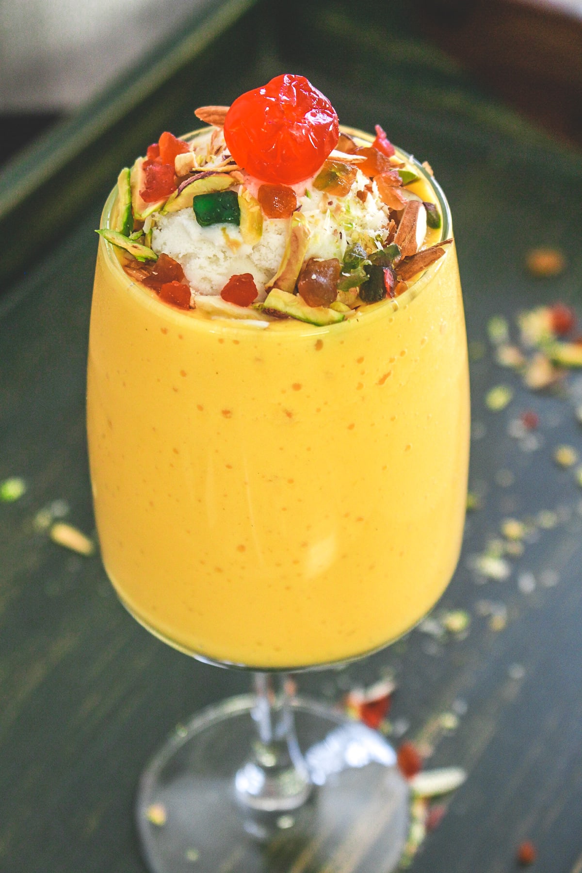 Mango mastani garnished with ice cream, nuts, turri frutti and cherry.