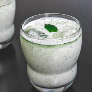2 glasses of pudina chaas garnished with a mint leaf.