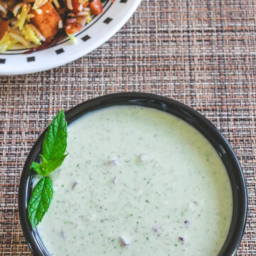 Mint raita garnished with mint leaves and served with biryani.