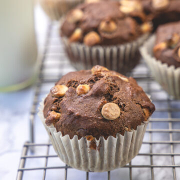 Close up of mocha muffin on the cooling rack with milk bottle and more muffins in the back.