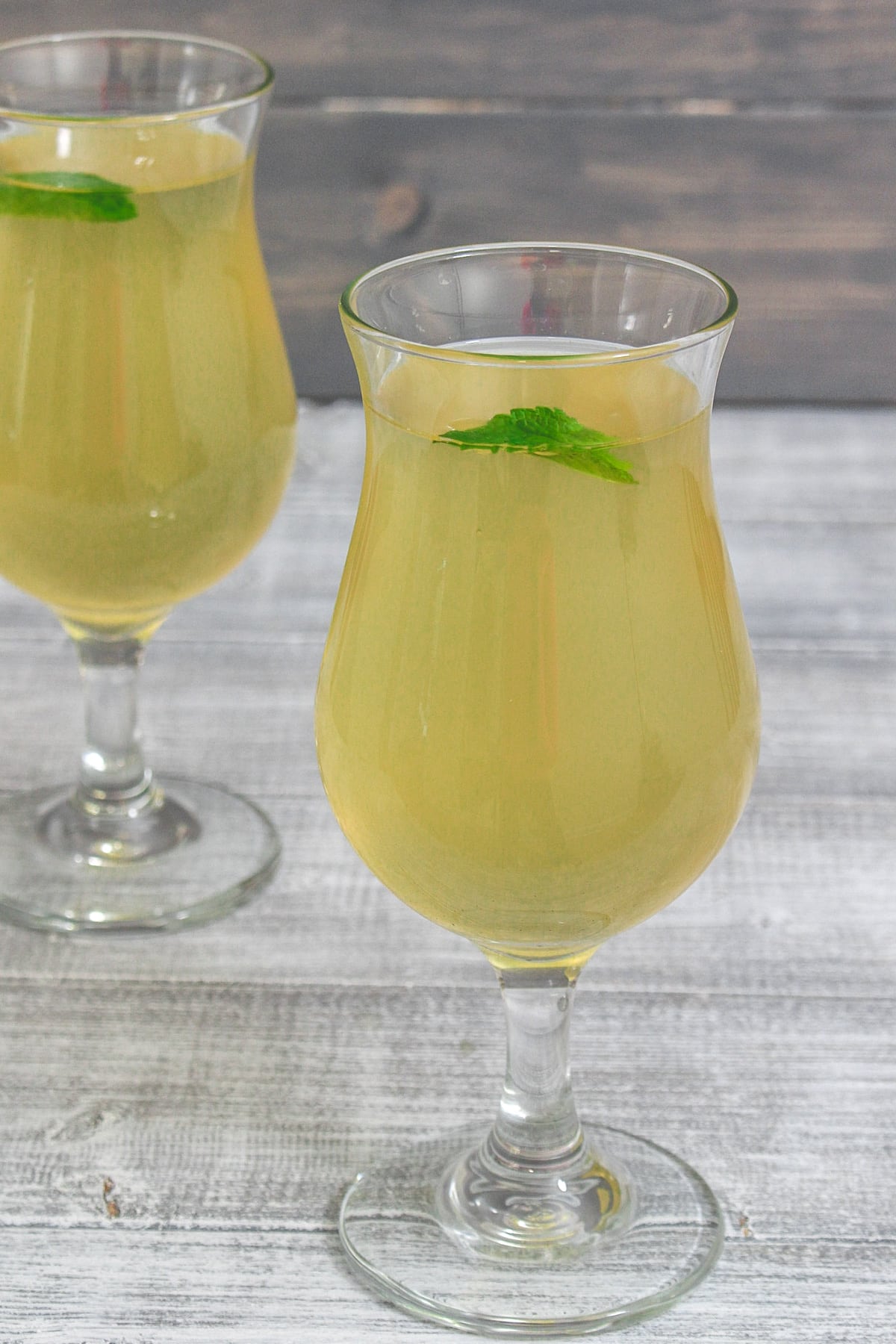 2 glasses of nimbu pani garnished with mint leaves.
