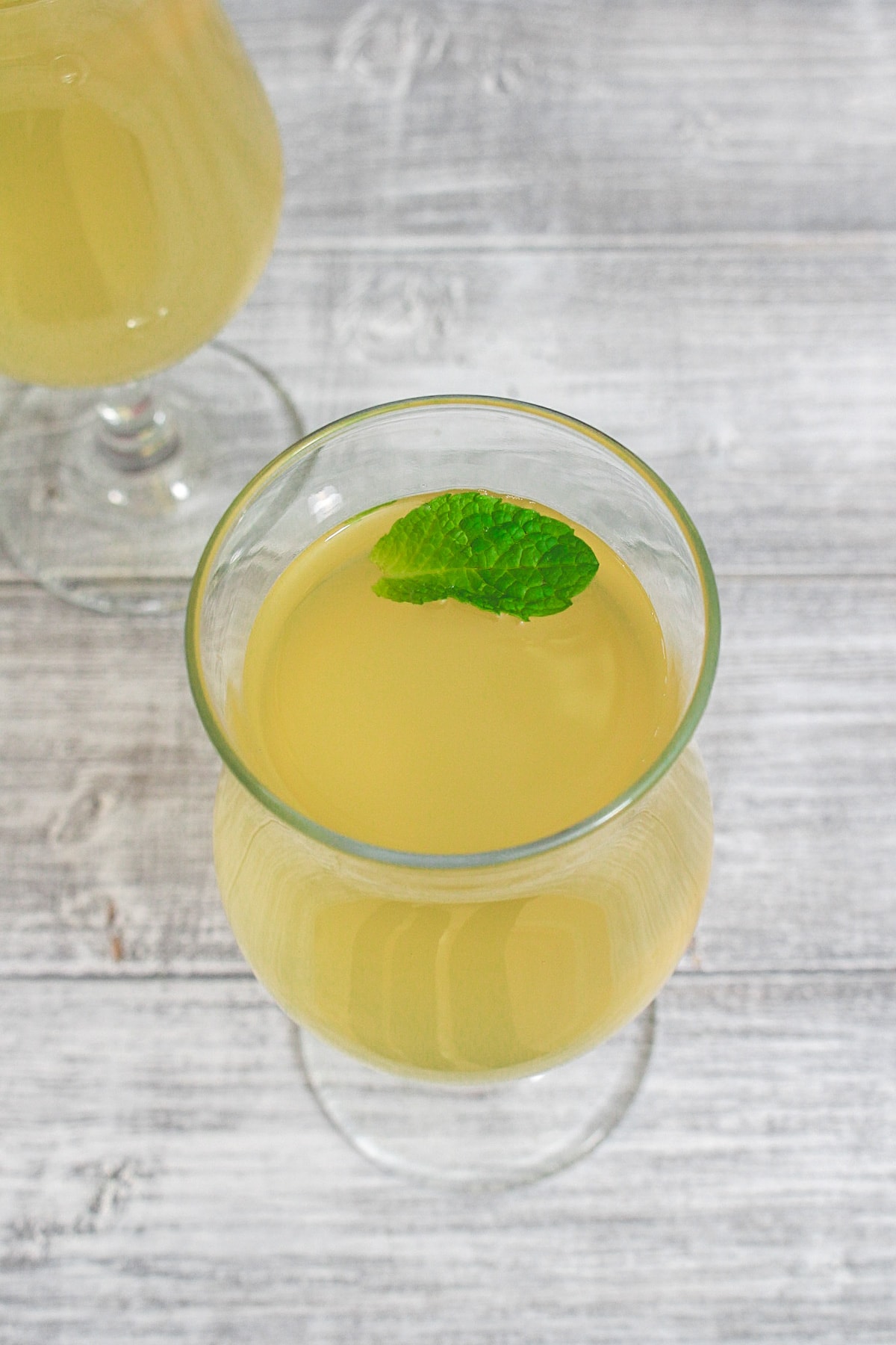 Nimbu pani garnished with a mint leaf and another glass in the back.