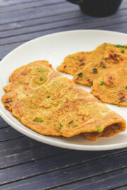 One oats chilla folded in half and one cut into triangle served in a plate.