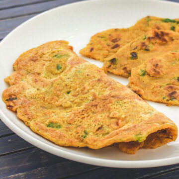 One oats chilla folded in half and one cut into triangle served in a plate.