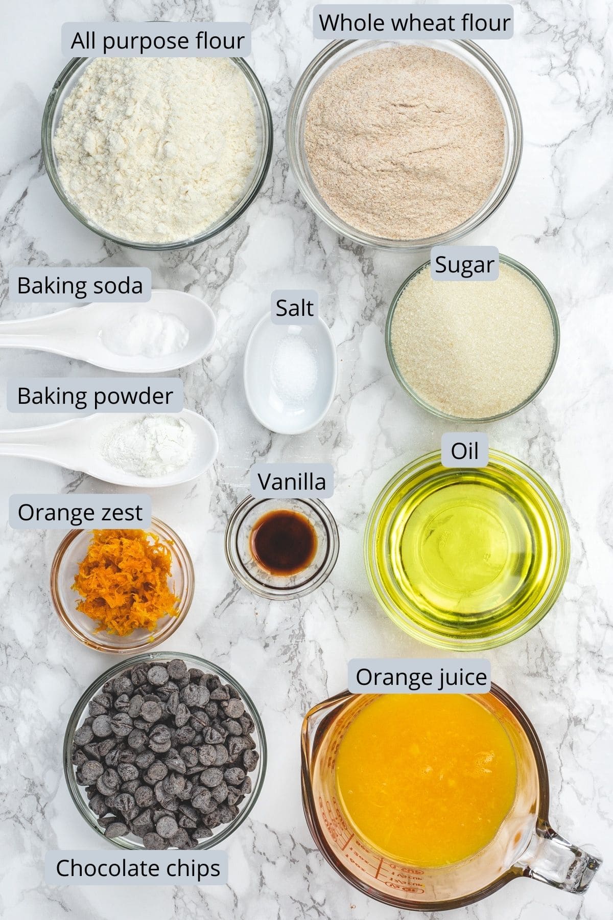 Orange muffin ingredients in individual bowls and spoons.