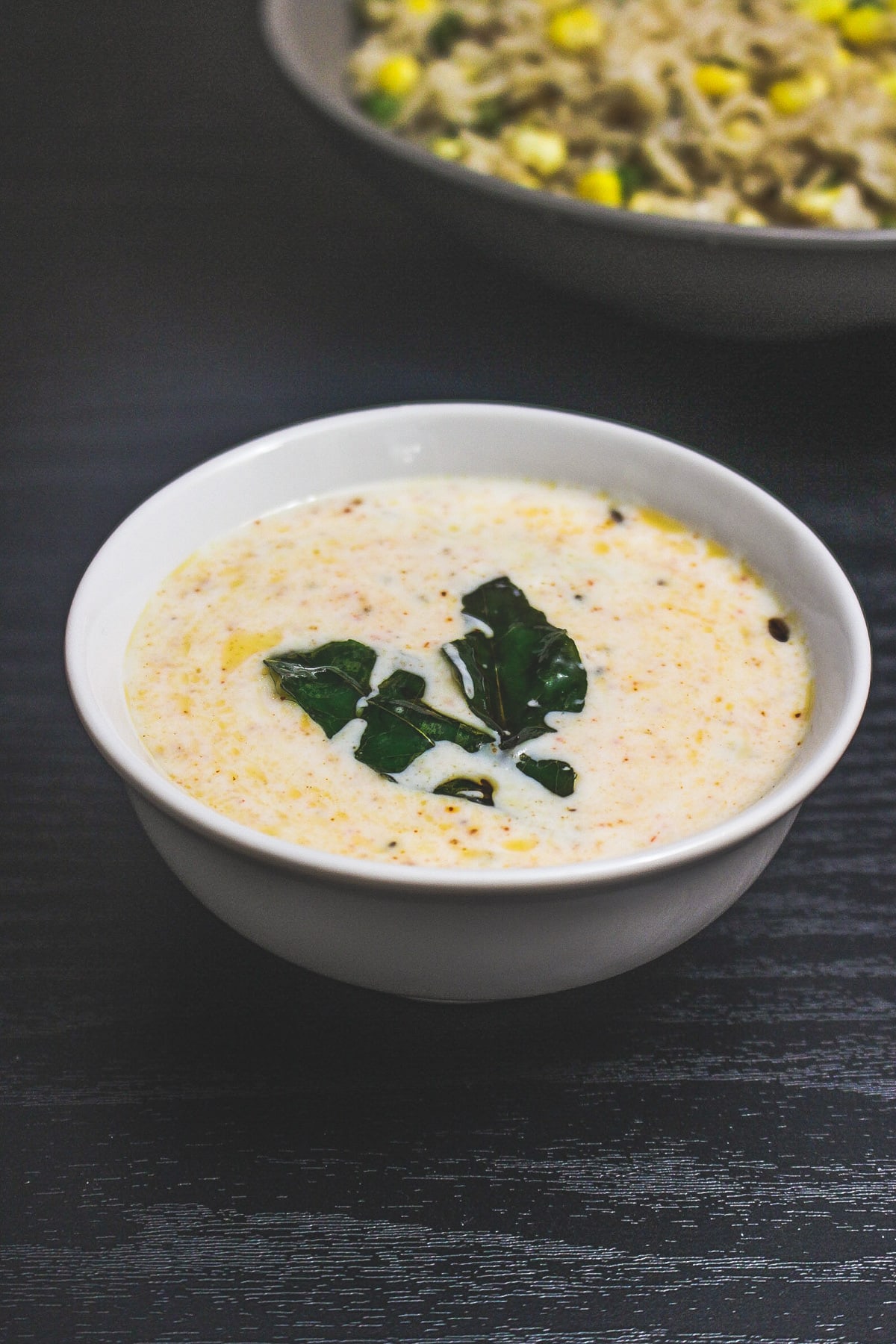 Plain tadka raita with curry leaves on top served with corn pulao.