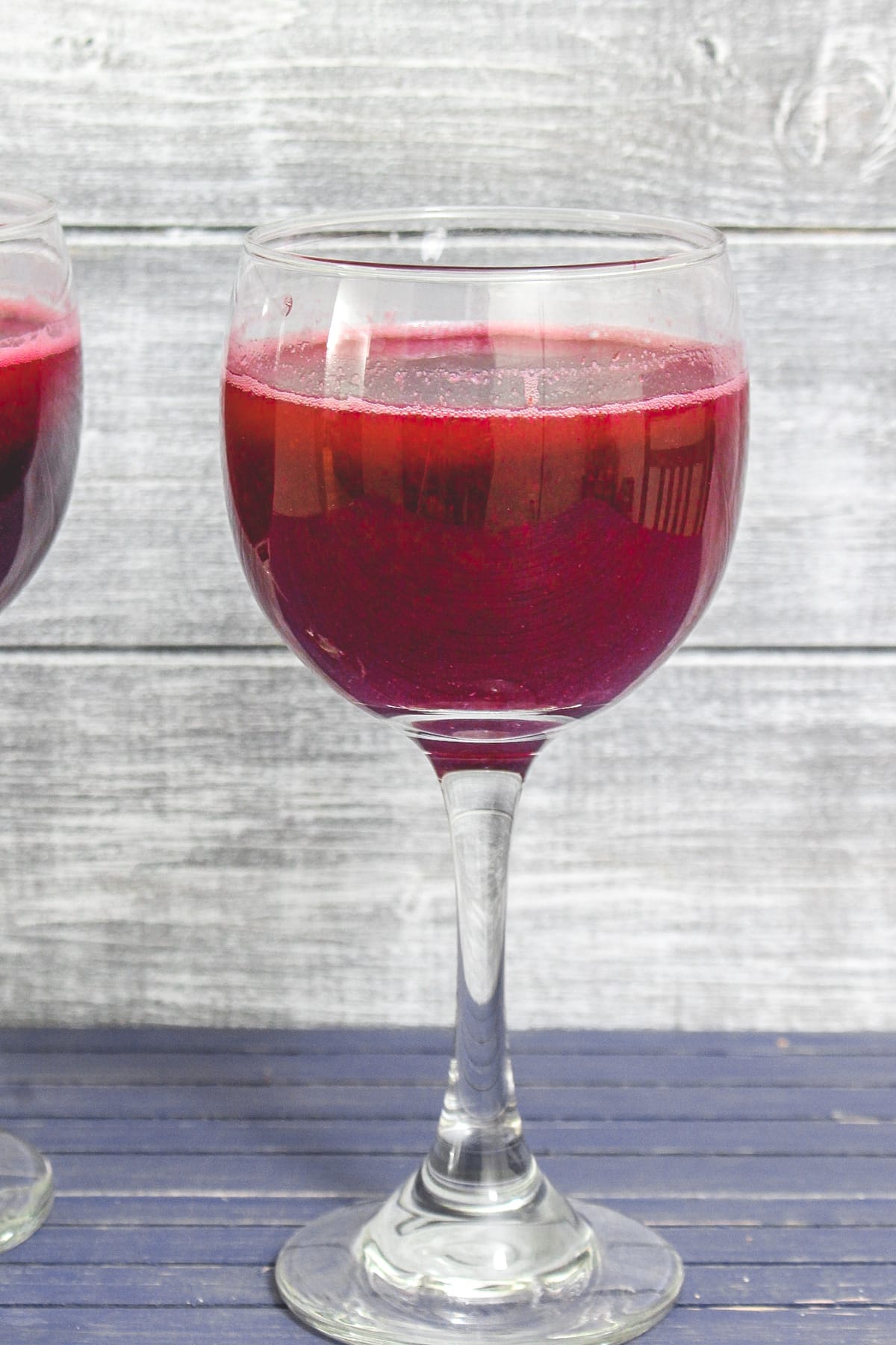 A glass of pomegranate juice with another glass on the side.