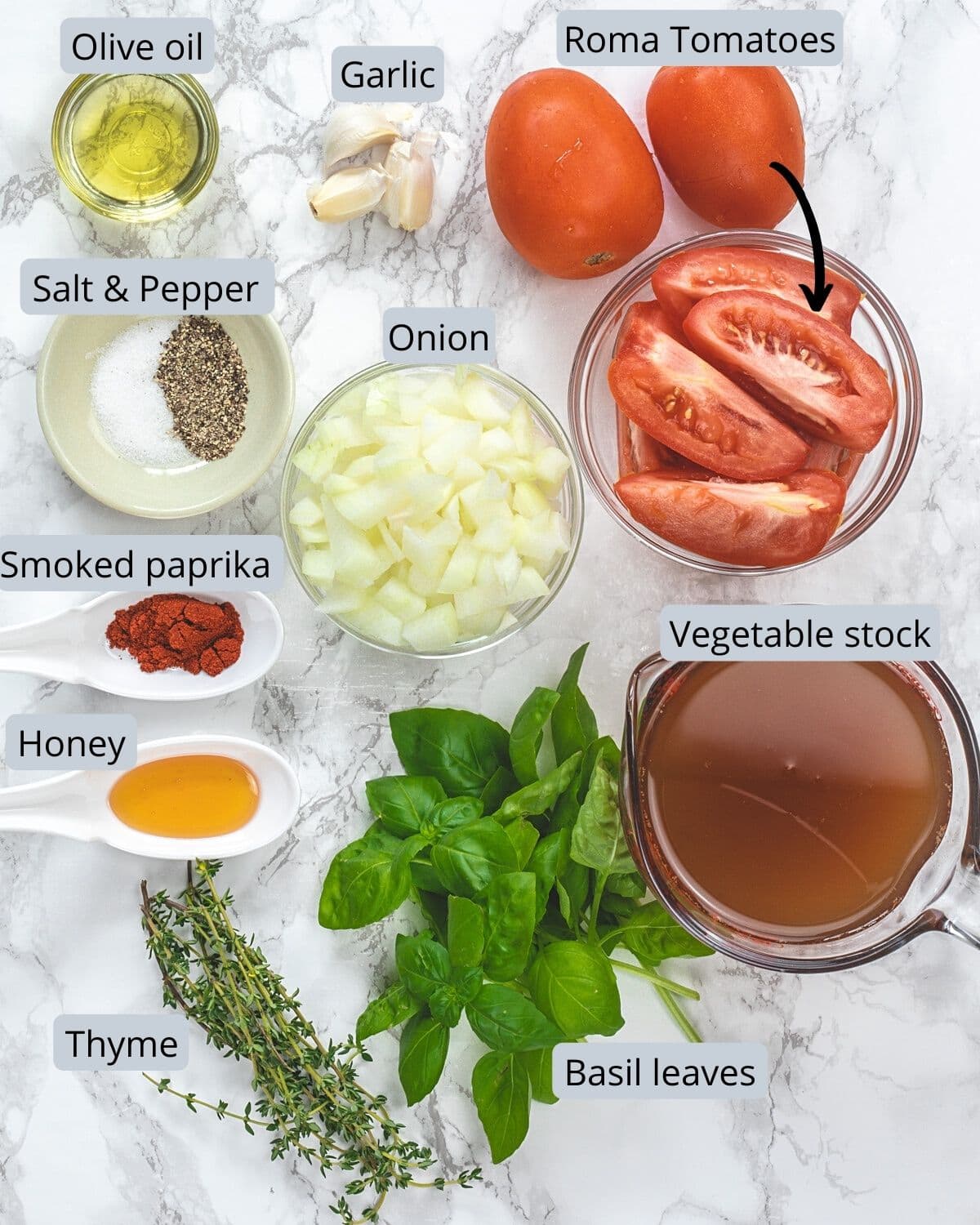 Ingredients for roasted tomato soup in individual bowls and on marble surface.