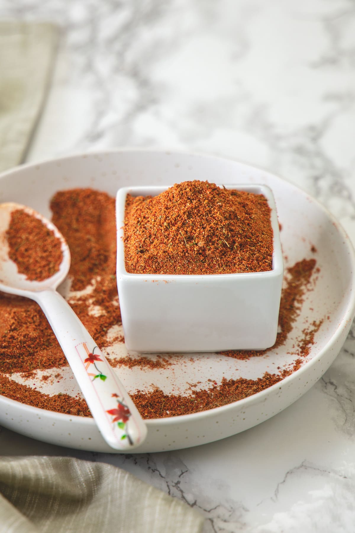 Tikka masala spice mix in a plate and bowl with spoon on the side.