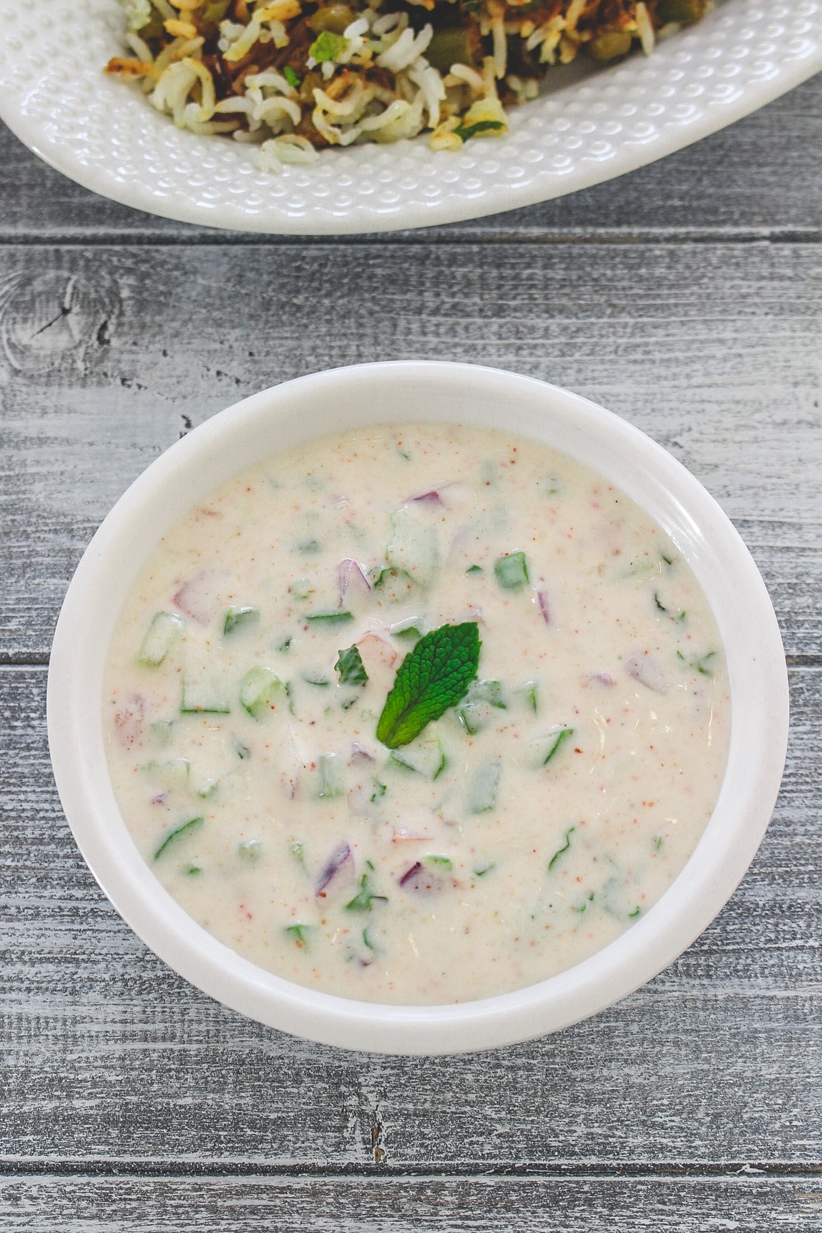 Vegetable raita garnished with mint leaf and served with veg biryani.