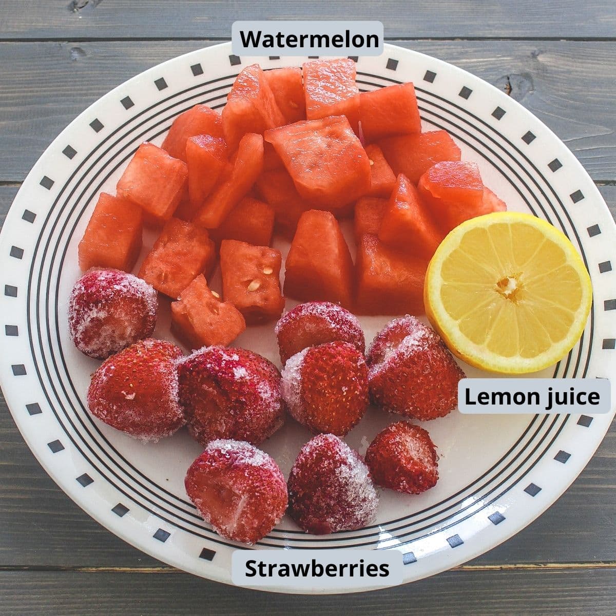 Frozen strawberries, watermelon cubes and half lemon in a plate.
