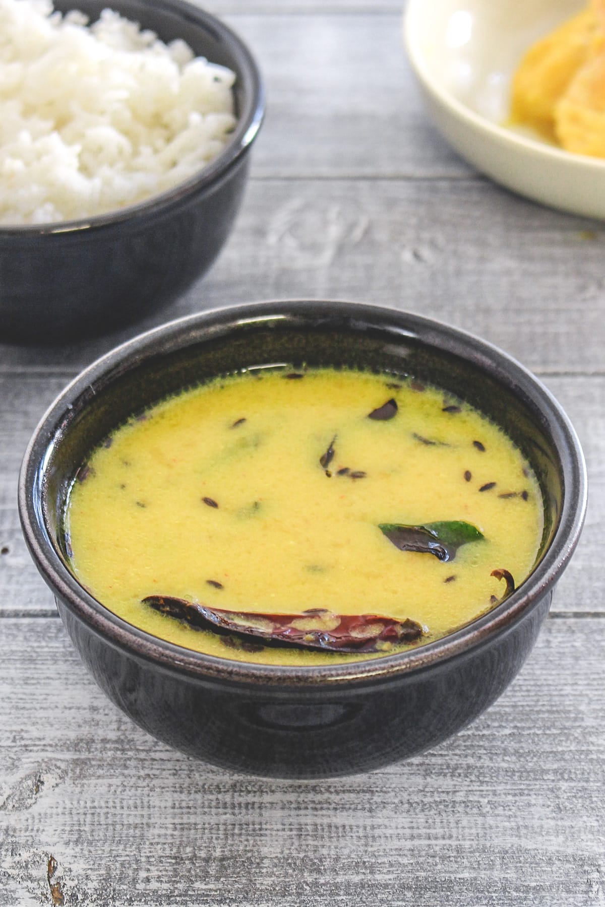 Fajeto served in a black bowl with a bowl of rice in back.